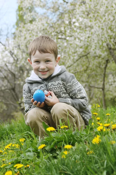 Pojke med eastre ägg bland vårträdgård — Stockfoto