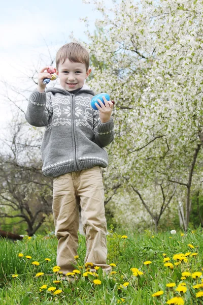 Pojke söker påskägg bland gräs — Stockfoto