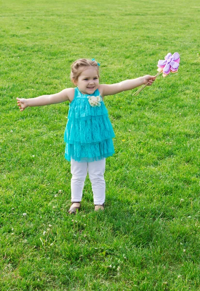 Petite fille parmi la prairie verte avec des fleurs — Photo