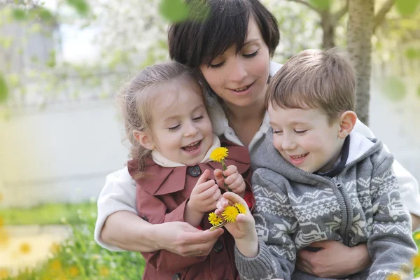 Matka a dvě děti obdivováním jarní zahrada — Stock fotografie