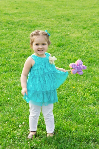 Klein meisje onder groene weide met bloemen — Stockfoto