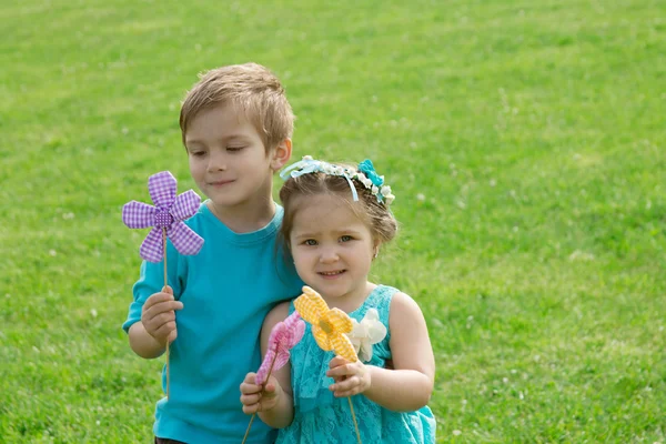 Soeur et frère jouant avec les fleurs dans l'herbe verte — Photo