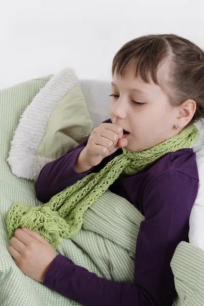 Girl coughs lying in bed with scarf — Stock Photo, Image