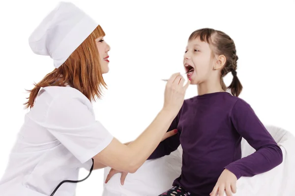 Doctor checking the throat of a young patient girl over white — Stock Photo, Image