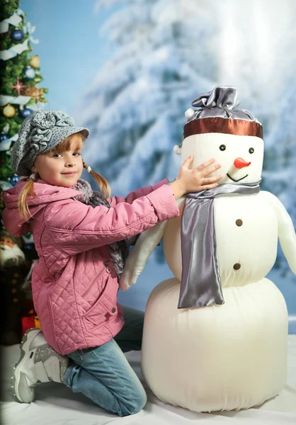Menina com um boneco de neve no fundo de uma paisagem de inverno — Fotografia de Stock