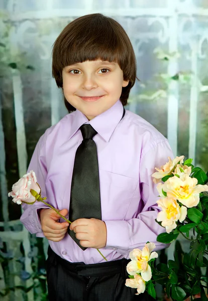 Портрет милого мальчика в фиолетовой рубашке с розой на зеленом — стоковое фото