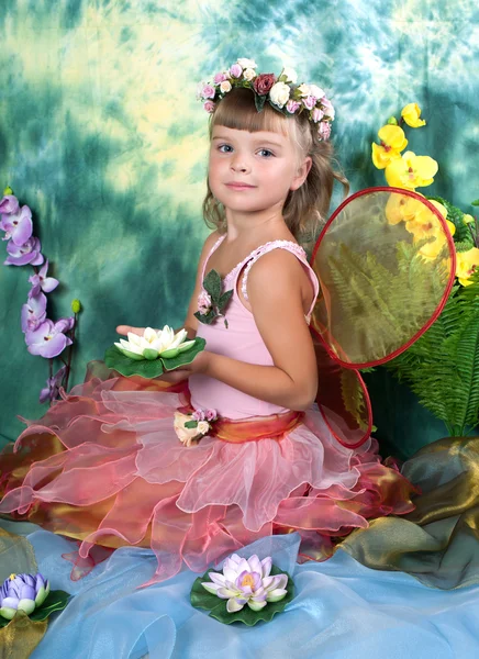 Mooi meisje in een lichte jurk met vleugels in een krans op een gree — Stockfoto