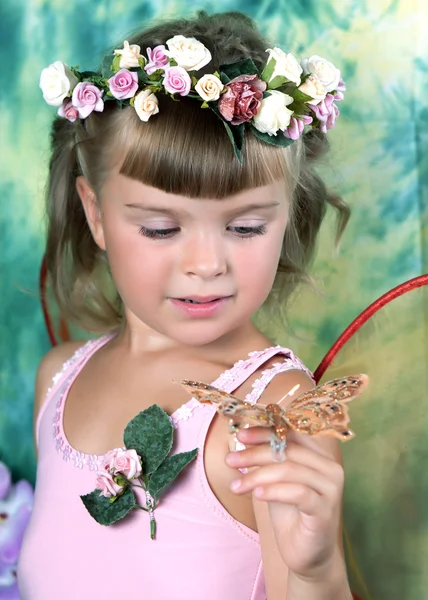 Menina bonita em um vestido rosa com asas em uma grinalda em um verde — Fotografia de Stock