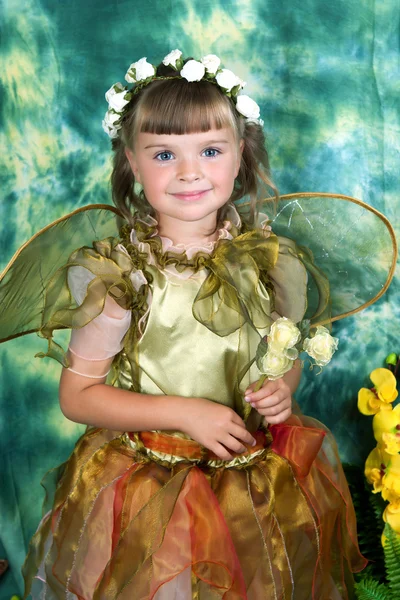 Menina bonita em um vestido verde com asas em uma grinalda em um gree — Fotografia de Stock