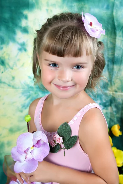 Schöne Mädchen in einem hellen Kleid mit Lavendelorchideen auf einem grünen — Stockfoto
