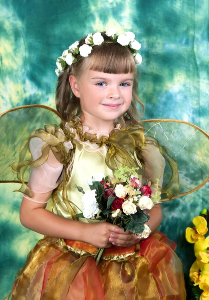 Mooi meisje in een lichte jurk met vleugels in een krans op een gree — Stockfoto