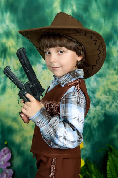 Mignon garçon en costume de cow-boy avec des armes sur un fond vert — Photo