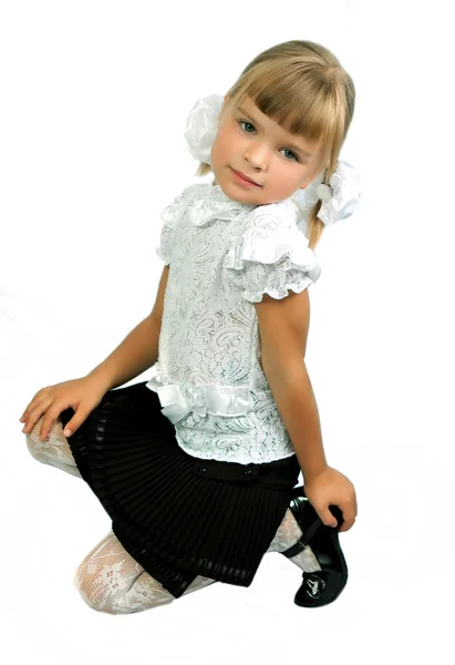 Première année fille en uniforme scolaire assis sur un fond blanc — Photo