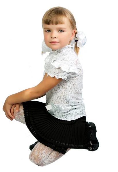 Première année fille en uniforme scolaire assis sur un fond blanc — Photo