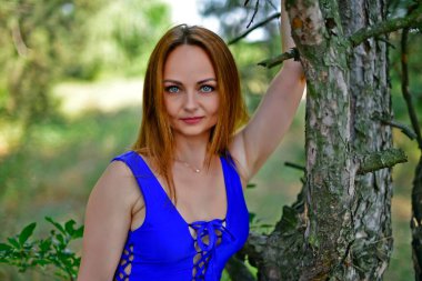 Güzel bir genç kadın, mavi bir mayoyla, sıradışı bir ağaçta..