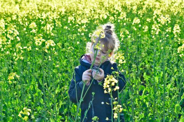 Bir kız çocuğu baharda evcil hamsterıyla çiçek tarlasında yürür..