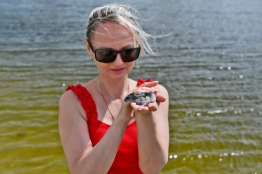 Güzel bir kadın ve kollarında nehir kenarında evcil bir hamster..