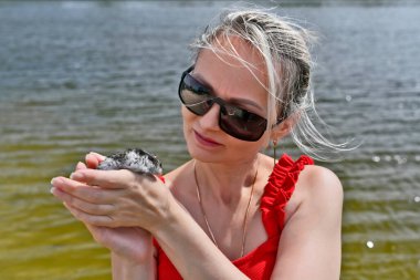 Güzel bir kadın ve kollarında nehir kenarında evcil bir hamster..