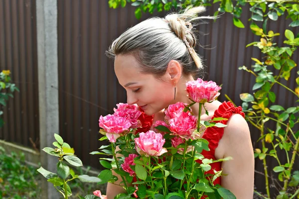 Beautiful woman in the country with a bush of beautiful roses.