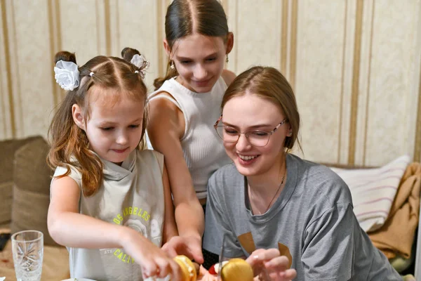 Granddaughters at their grandmother\'s birthday party eat a birthday cake.