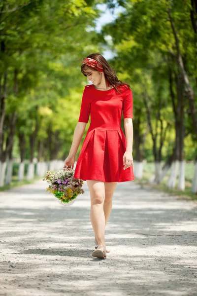 Kvinnan promenader med blommor korg — Stockfoto