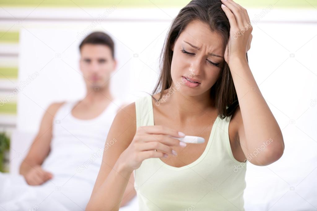 Upset woman looking in pregnancy test