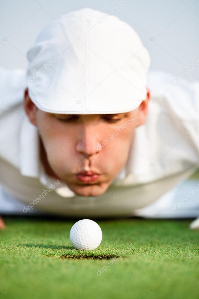 Close-up of man blowing on golf ball