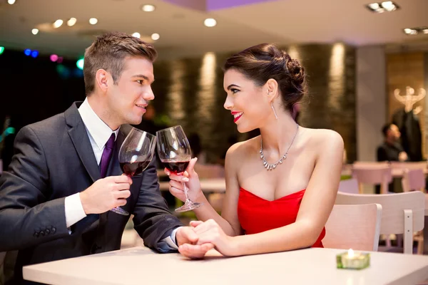 Glückliches Paar am Restauranttisch beim Anstoßen — Stockfoto