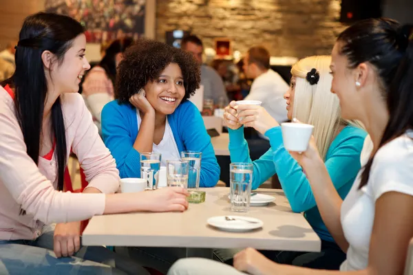 Four college chatting in a coffee shop Royalty Free Stock Images