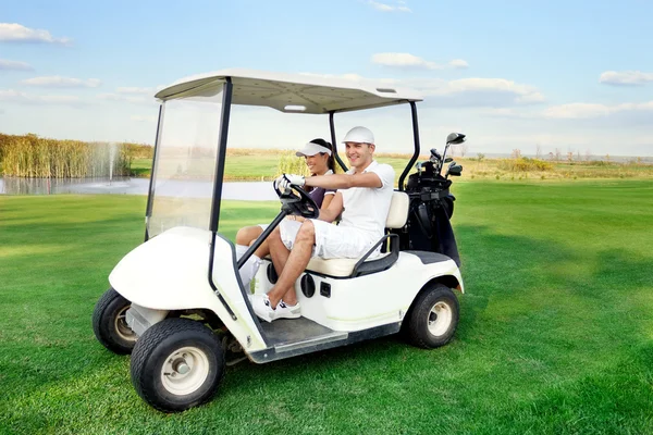 Feliz pareja conduciendo un carrito de golf — Foto de Stock