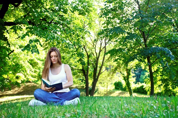 Jeune femme lisant dans le parc — Photo