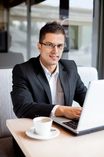 Homme d'affaires souriant assis au bureau avec ordinateur portable — Photo