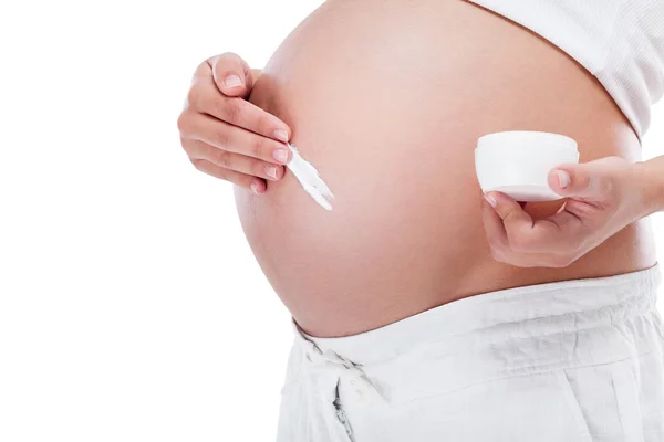 Donna incinta che si mette la crema sulla pancia — Foto Stock