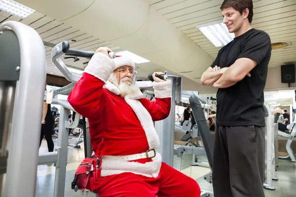 Weihnachtsmann mit Personal Trainer im Fitnessstudio — Stockfoto