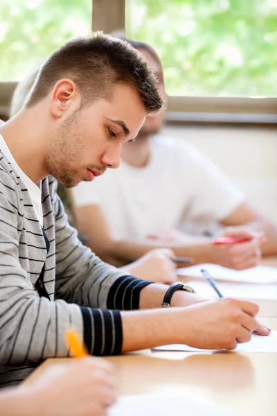 Manlig collegestudent sitter i ett klassrum — Stockfoto