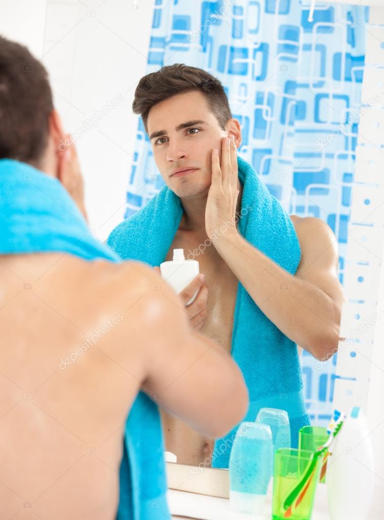 Young man applying after shave