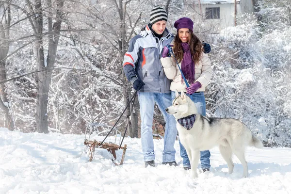 Paar mit Hund im verschneiten Wald — Stockfoto