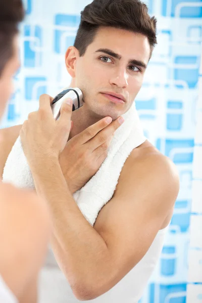전기 면도기와 그의 수염 떨어져 면도 하는 젊은 남자 — 스톡 사진