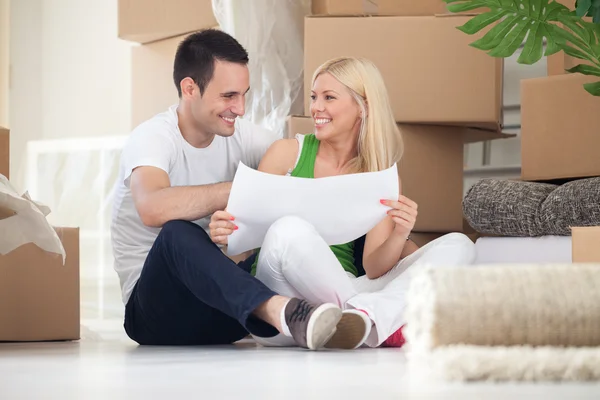 Paar zittend op de vloer te kijken naar huis plannen — Stockfoto