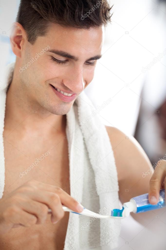 Young man squeezes toothpaste on the brush