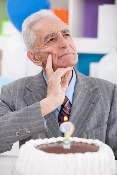 Thinking senior man with birthday cake — Stock Photo, Image