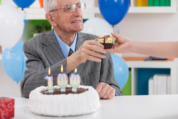 Smiling senior man receiving birthday gift — Stock Photo, Image