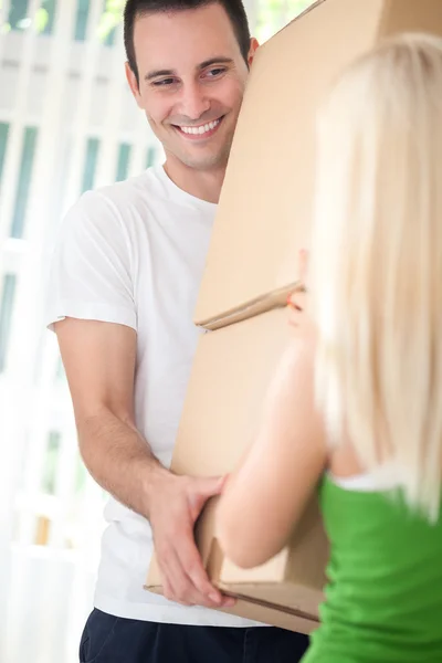 Pareja con cajas mudándose a un nuevo hogar, sonriendo — Foto de Stock