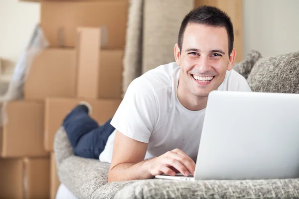 Homem feliz usando laptop em sua nova casa — Fotografia de Stock