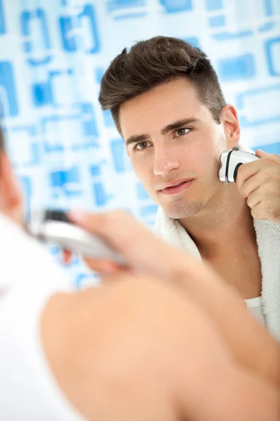 Человек бритья бороду с электробритвой — стоковое фото