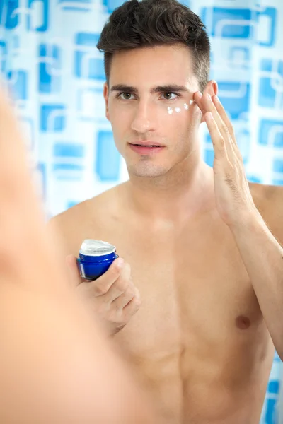 Homem bonito aplicando creme no rosto — Fotografia de Stock