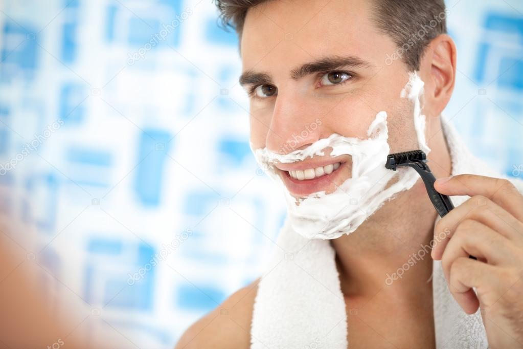 man shaving his beard with razor