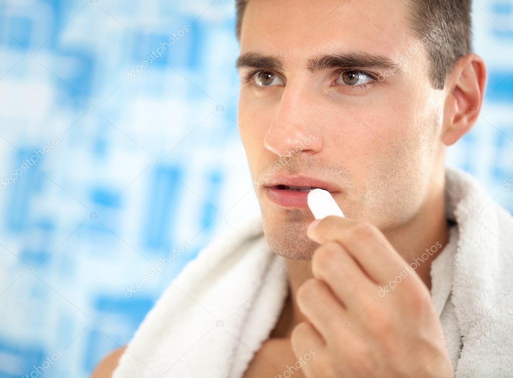 man applying balsam for lips