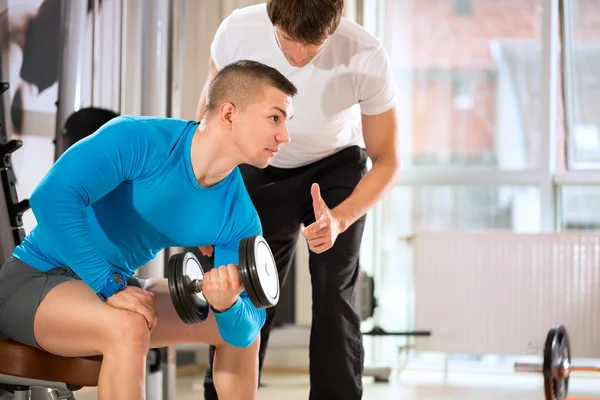 Hombre haciendo levantamiento de pesas con entrenador —  Fotos de Stock