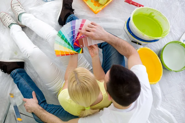 Casal sentado no chão cercado equipamento para pintura — Fotografia de Stock